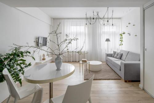 een witte woonkamer met een tafel en een bank bij Holečkova Apartments in Praag