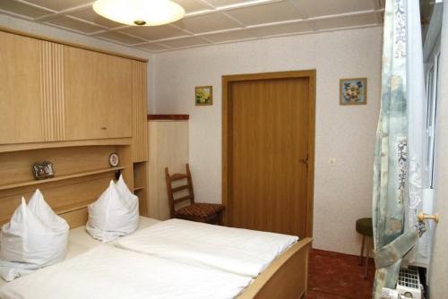 una camera da letto con un letto con cuscini bianchi di Ferienwohnung und Pension Jentsch a Markische Heide