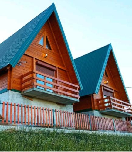 a wooden house with a blue roof and a fence at Holiday Homes B&V in Žabljak