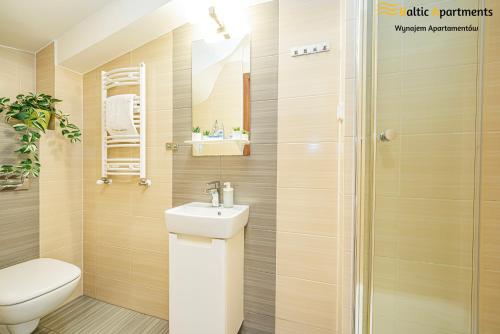 a bathroom with a toilet and a sink and a shower at Baltic Apartments - Hotelik Przy Promenadzie in Świnoujście