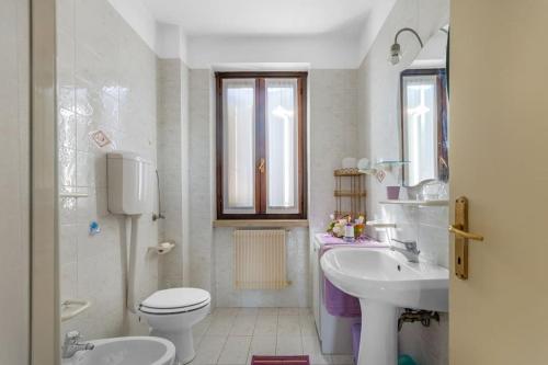 a white bathroom with a toilet and a sink at Cherry House with Pool, Solarium Area and Barbecue in Manerba del Garda