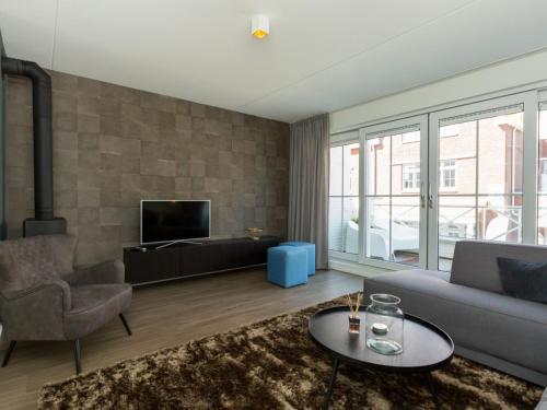a living room with a couch and a tv at Luxury apartment with Sauna the foot of the dunes in Koudekerke