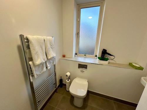 een badkamer met een toilet, een raam en handdoeken bij Big Cozy Room near City Center in Dublin