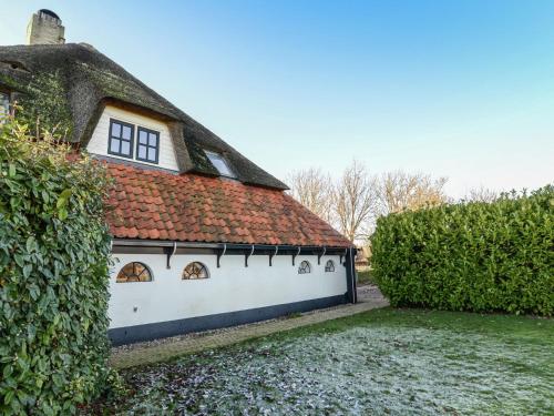 an old house with a thatched roof and a hedge at Lovely Holiday Home in Texel near Sea in Oost