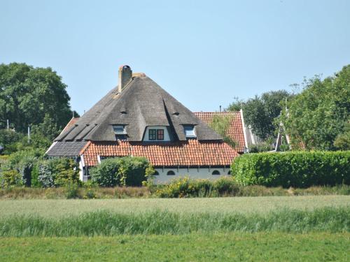 una casa antigua con techo de paja en un campo en Lovely Holiday Home in Texel near Sea, en Oost