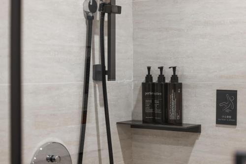 a shower with three bottles on a shelf in a bathroom at UrCove by HYATT Beijing Forbidden City in Beijing