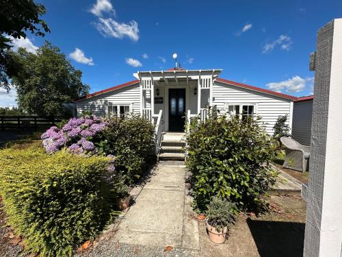 a white house with a door and some bushes at The Cottage at The Willows in Cambridge