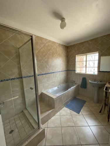 a bathroom with a shower and a tub and a sink at Vaaldam @ Sgt Pepper’s Holiday Home in Oranjeville