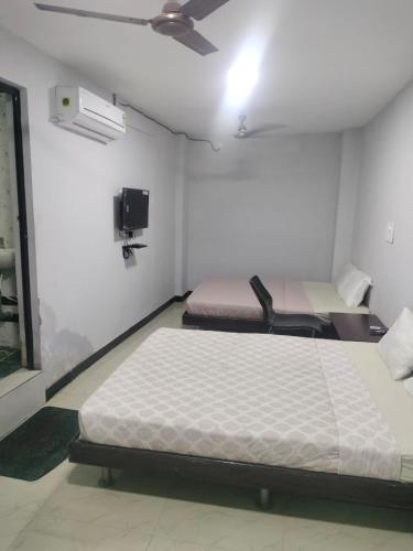 two beds in a small room with a fan at AB Residency in Coimbatore