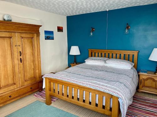 a bedroom with a wooden bed and a blue wall at Tornaroan Cottage in Ballycastle