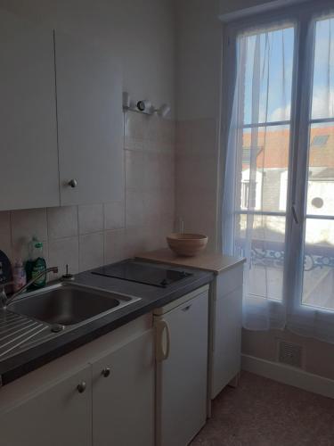 une cuisine blanche avec un évier et une fenêtre dans l'établissement Cabourg Charmant studio centre ville RUE DE LA MER, à Cabourg