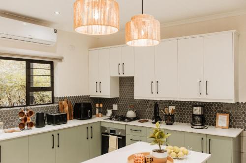 a kitchen with white cabinets and white counter tops at Chawal @ Swartwithpens in Marloth Park