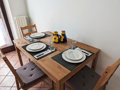 einen Holztisch mit Tellern und Weingläsern darauf in der Unterkunft Sentirsi a casa in Verzuolo