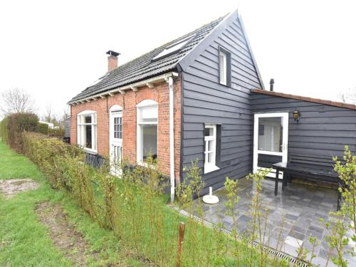 een zwart huis met een bankje ervoor bij Quaint Holiday Home in Nieuwvliet Bad near Seabeach in Nieuwvliet-Bad