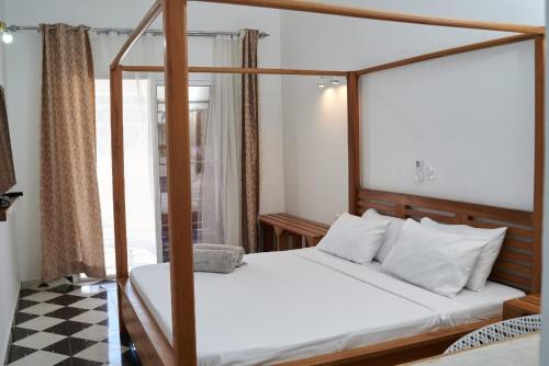a bedroom with a four poster bed and a checkered floor at JIRAJIRA HOTEL in Nosy Be