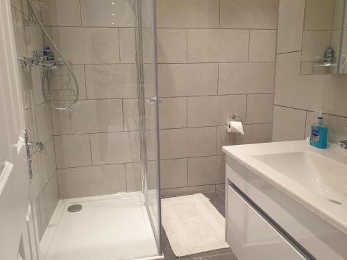 y baño con ducha y lavamanos. en New - Spacious London 1 bedroom king bed apartment in quiet street near parks 1072gar, en Londres
