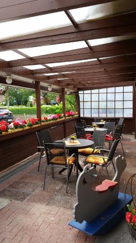 a patio with tables and chairs in a restaurant at Pension am Kurgarten in Bensersiel
