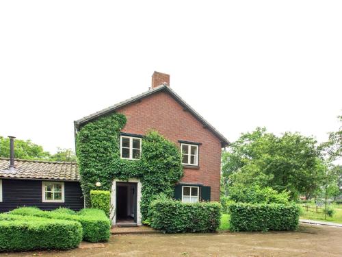 una casa de ladrillo rojo con hiedra verde. en Cozy group house in Reusel in a natural environment en Lage Mierde