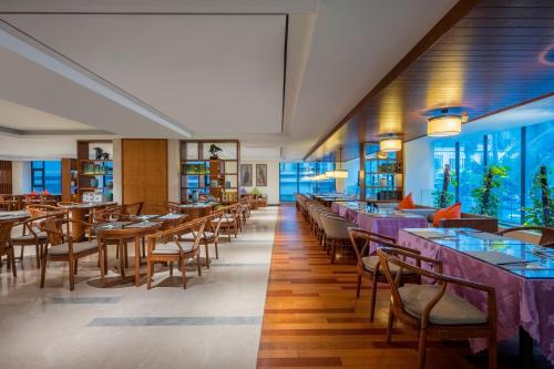 a restaurant with tables and chairs and windows at SSAW Boutique Hotel Sanya in Sanya