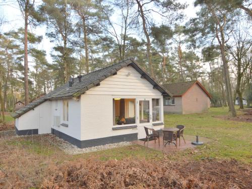 Casa blanca pequeña con mesa y sillas en Completely detached bungalow in a nature filled park by a large fen, en Stramproy