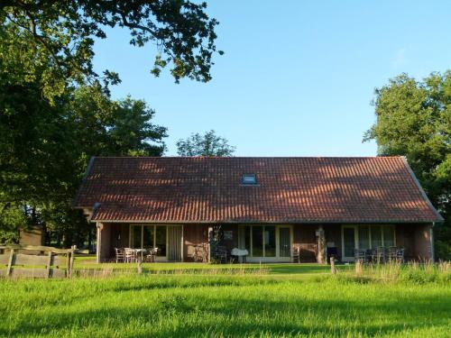 GeesterenにあるHoliday Home in Geesteren with Roof Terrace Garden Furnitureの畑の赤屋根の家