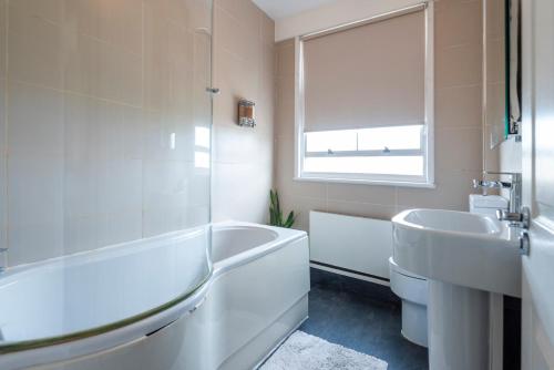 a white bathroom with a tub and a sink at Dazzling Room near Paddington/Elizabeth Stn in London
