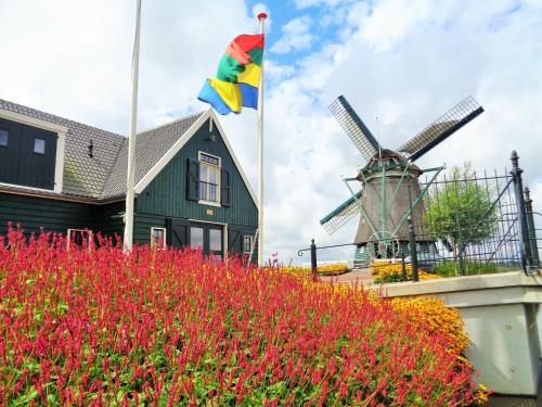 ein Haus mit einer Flagge und einer Windmühle in der Unterkunft Spacious Holiday Home in the Beemster near a Windmill in Middenbeemster