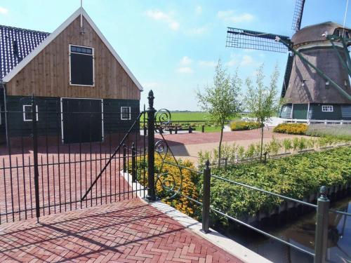 Spacious Holiday Home in the Beemster near a Windmill في Middenbeemster: سور بجانب حظيرة وطاحونة