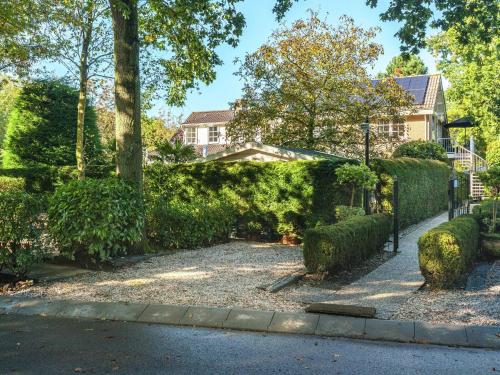 um jardim com arbustos e uma cerca com uma casa em Quaint Apartment in Oostkapelle Zealand with Terrace em Oostkapelle