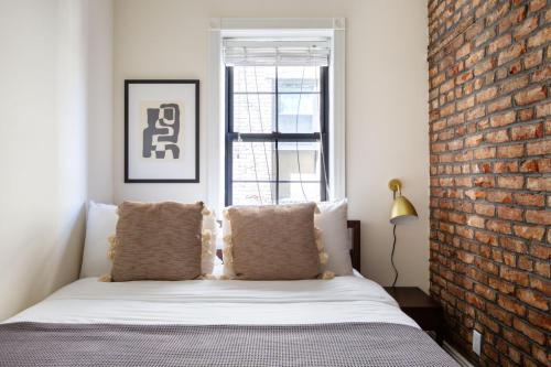 a bedroom with a brick wall and a bed with pillows at West Village 1br w wd nr bars restaurants NYC-1133 in New York