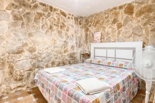 een slaapkamer met een bed en een stenen muur bij Cueva Alicante in Alicante