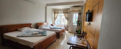 a small room with two beds and a television at Nhà nghỉ Ban Mai in Ha Long