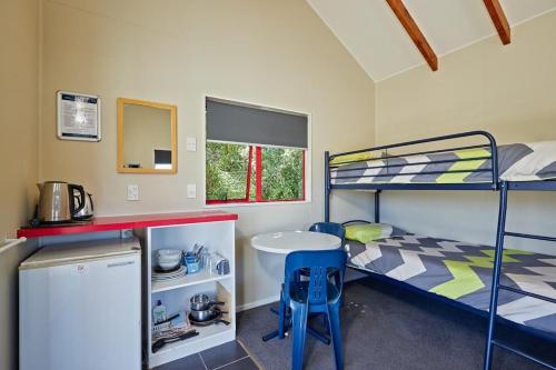 Ce dortoir comprend des lits superposés et une table. dans l'établissement Kaikoura TOP 10 Holiday Park, à Kaikoura