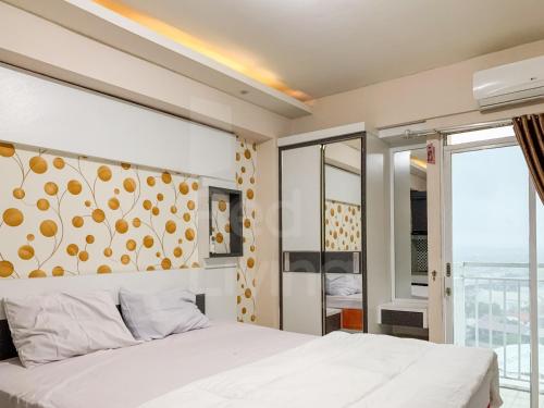 a bedroom with a white bed and a large window at RedLiving Apartemen Bogor Valley - Paulina Property Tower A in Kalibata 1