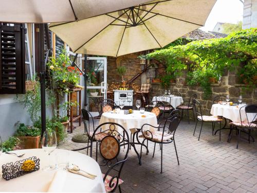 a patio with tables and chairs and an umbrella at Rooms & Restaurant Ostarija in Dolenjske Toplice