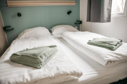 Dos camas blancas en una habitación con toallas. en Cahita Camping Belle-Vue 2000 en Berdorf