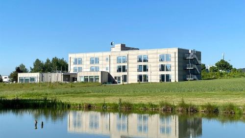 a building on a hill next to a body of water at Avaneo Hotel Marktredwitz in Marktredwitz