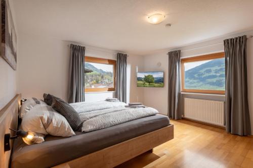a bedroom with a bed and two windows at Apartments Gondelspaß in Fügen