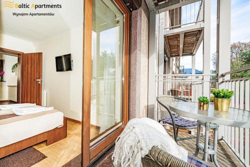 a room with a balcony with a bed and a table at Baltic Apartments - Hotelik Przy Promenadzie in Świnoujście