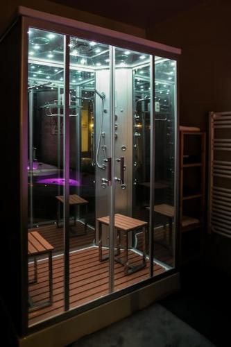 Cette chambre dispose d'une porte en verre avec une douche et une table. dans l'établissement Une Parenthèse, gîte de charme et spa., à Sainte-Luce-sur-Loire