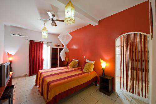 a bedroom with a bed with an orange wall at La Maison Abaka in Dakar