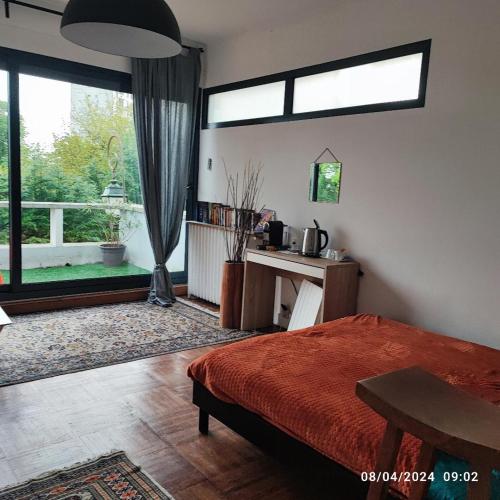 a bedroom with a bed and a desk and a window at chambre tt confort dans un coin de verdure près de Paris in Le Pecq