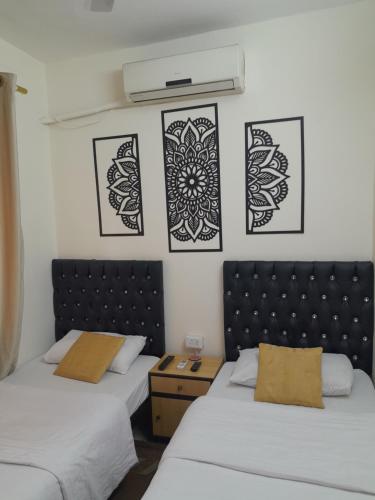 duas camas num quarto com arte em preto e branco na parede em Hamoudah Hotel em Amã