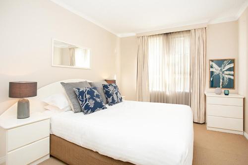 a white bedroom with a bed and a window at Harbourside Apartment with Spectacular Pool in Sydney