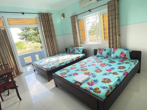 een slaapkamer met 2 bedden en een raam bij Nhà nghỉ Vân Châu-Cát Tường in Ấp Chô Bên