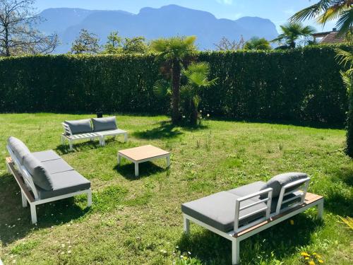three lounge chairs and a table in the grass at Sonnenresidence Alpenhof in Termeno