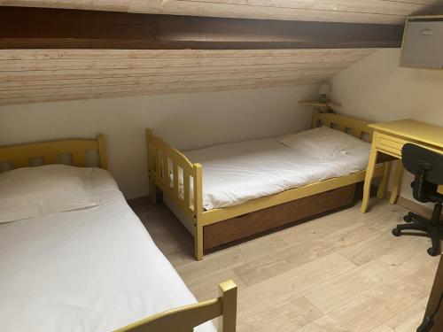 two twin beds in a room with a desk and a desk at Gite de Belle vue in Semur-en-Brionnais