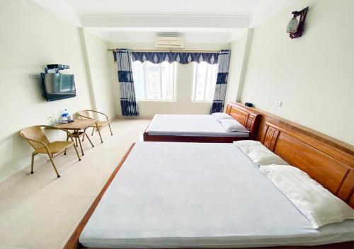 2 Betten in einem Zimmer mit Tisch und Stühlen in der Unterkunft Coto Plus Hotel & Restaurant in Provinz Quang Ninh