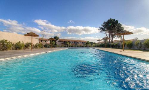- une piscine d'eau bleue avec des parasols dans l'établissement Villa CORSICA SUN, Résidence Cala Rossa Bay, à Lecci