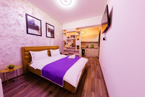 1 dormitorio con 1 cama grande con manta morada en Luxury Lazar Towers Palas Mall Area, en Iaşi